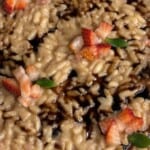 Creamy risotto topped with diced fresh strawberries, small green leaves, and drizzled with a dark balsamic glaze.