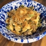 Orecchiette pasta with sausage and greens, topped with breadcrumbs in a blue and white splatter-pattern bowl.
