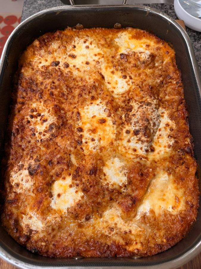 A rectangular baking dish filled with a baked lasagna topped with melted, browned cheese.