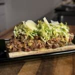 Beef tartare served on a roasted bone, topped with frisée and shaved parmesan.