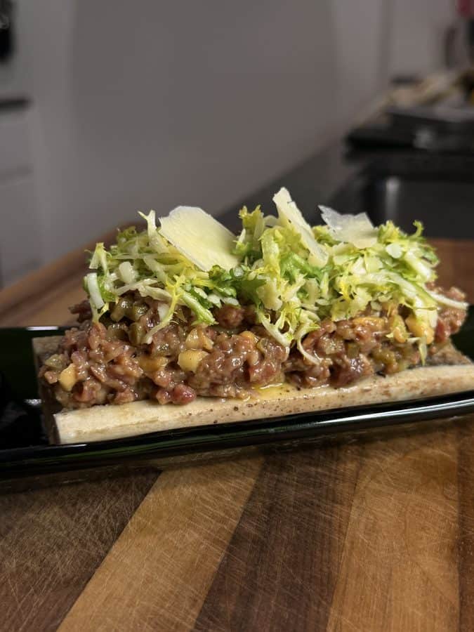 Beef tartare served on a roasted bone, topped with frisée and shaved parmesan.